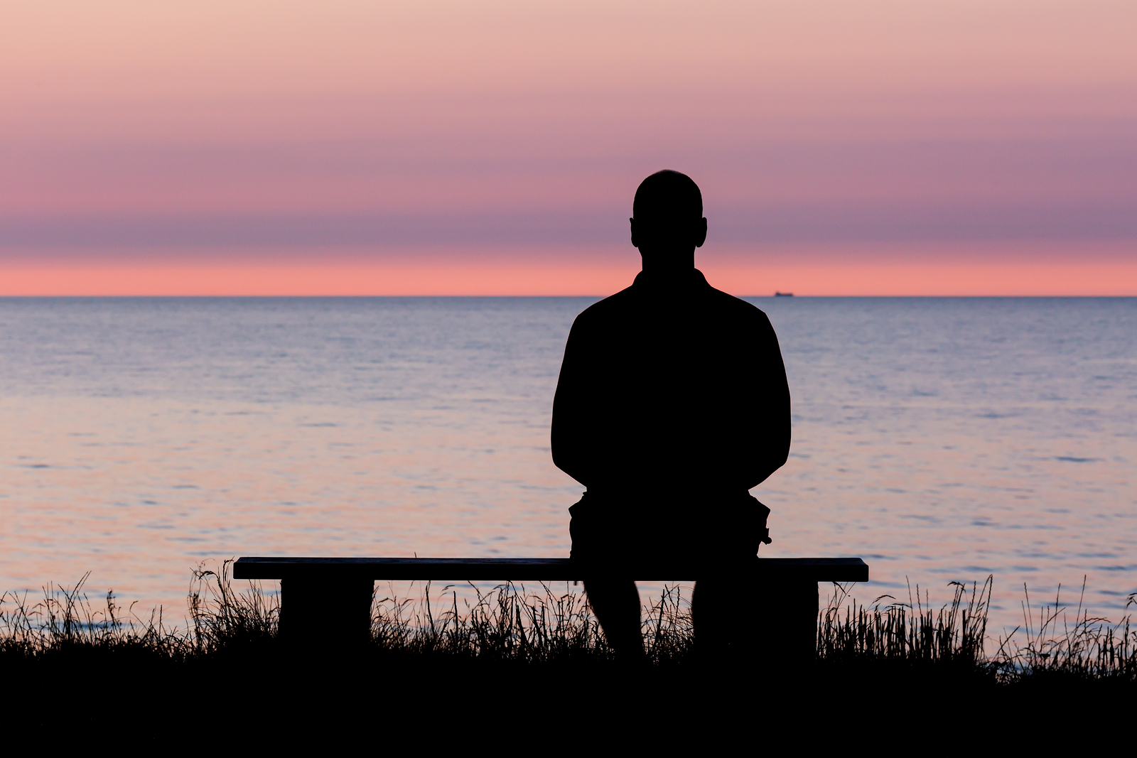 Silhouette of male person against a colorful horizon.